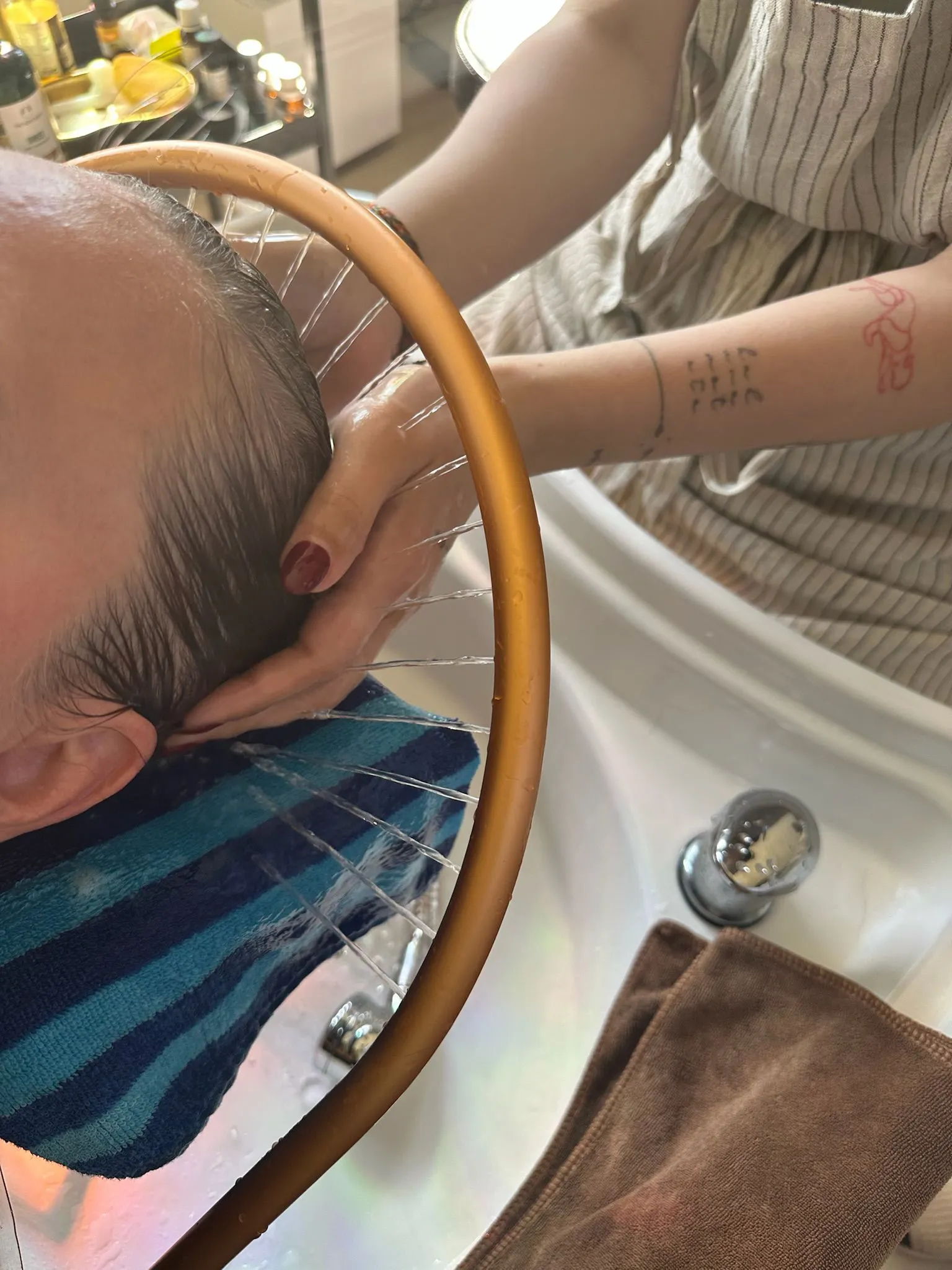 Lyhythiuksisen miehen päänahkaa pestään lämpimän vesisuihkun alla Signature Head Spa -hoidossa Aura Beautyssa Espoossa