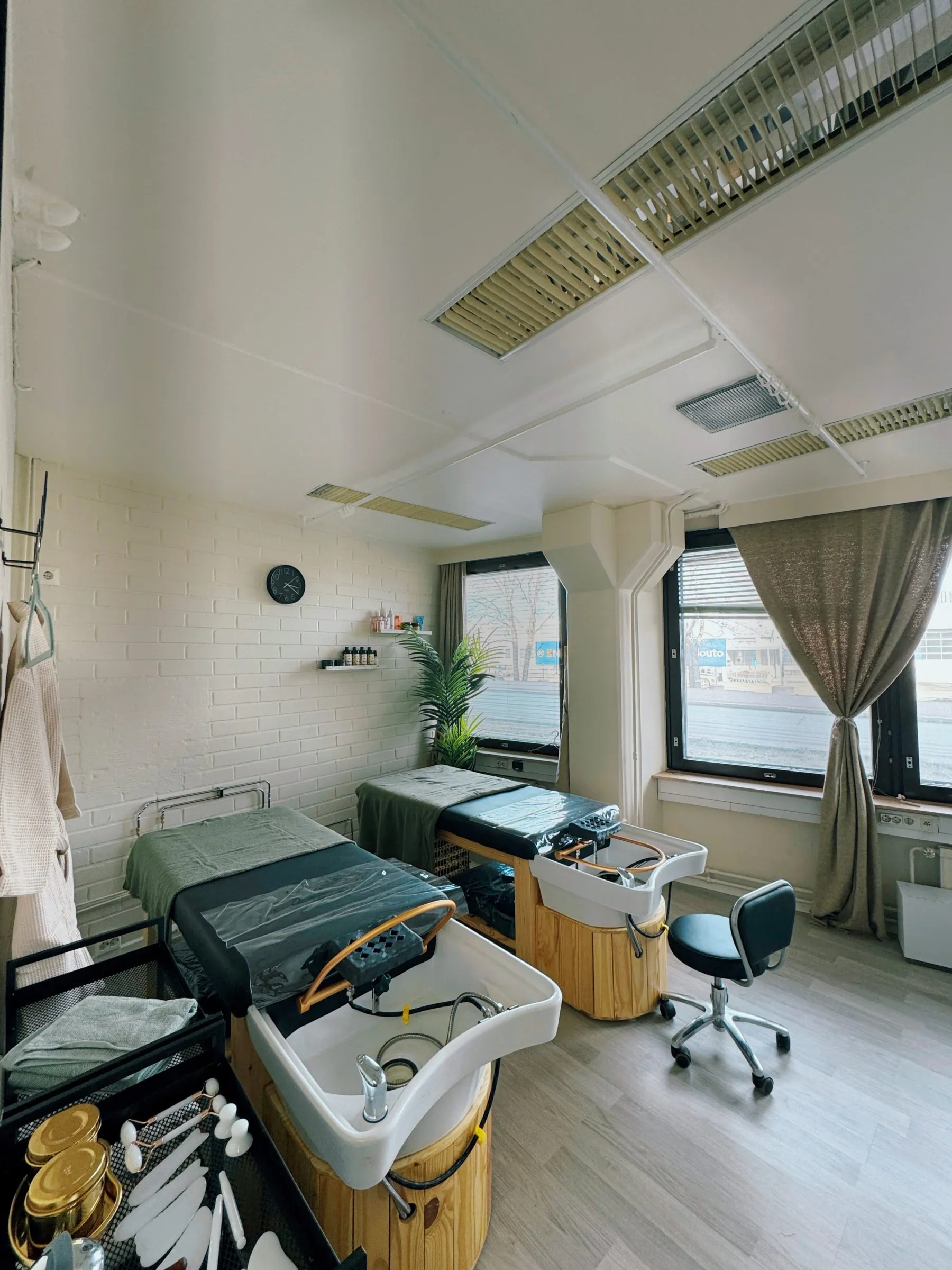 Kaksi head spa -hoitopöytää pesualtaineen vierekkäin valoisassa hoitohuoneessa Aura Beautyssa